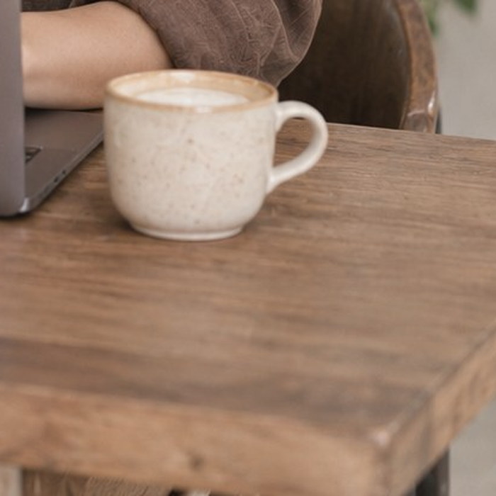 A cup of coffee beside a laptop on a wooden table